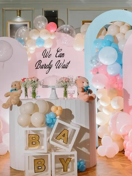 This full view of our teddy bear gender reveal setup shows how we use arched backdrops and cascading balloon garlands in pink and blue to create a visually stunning focal point. The theme is tied together with teddy bears and "BABY" blocks.