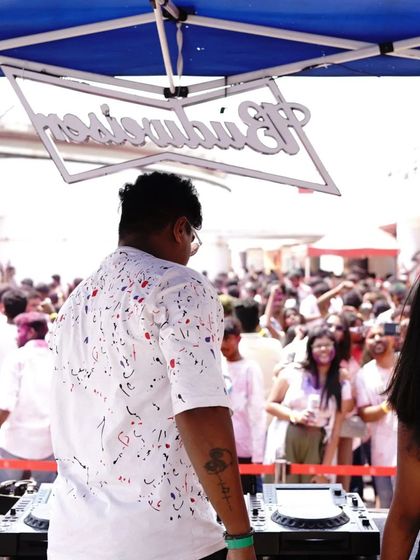 A shot from behind the decks at a Holi party, looking out at the sea of people dressed in white, ready to be covered in color.