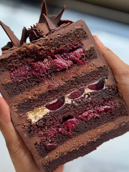 A cross-section of my Modern Black Forest cake. It has layers of moist chocolate cake, cherry filling, creamy whipped ganache, and luscious whipped dairy cream. It's a sophisticated take on a classic.