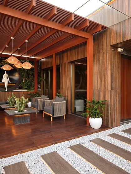 This terrace retreat is a serene fusion of nature's artistry and elegant design. The space combines warm wood decking and a pergola with a vertical green wall and a floor of pristine white stones, creating the perfect haven to unwind.