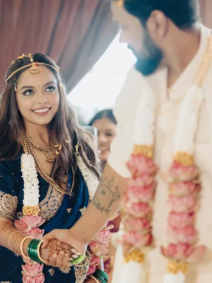 A sweet moment during the wedding ceremony. The bride's radiant smile and sparkling eyes are the focus, enhanced by a makeup look that is both traditional and fresh.