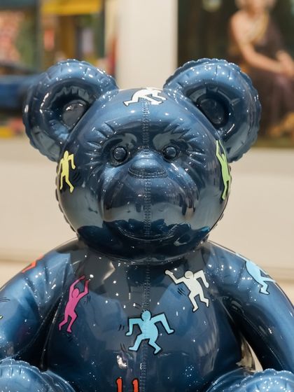 A close-up of the face of the "Ted – Ode To Keith Haring" sculpture, where the glossy blue finish and vibrant figures create a captivating effect.