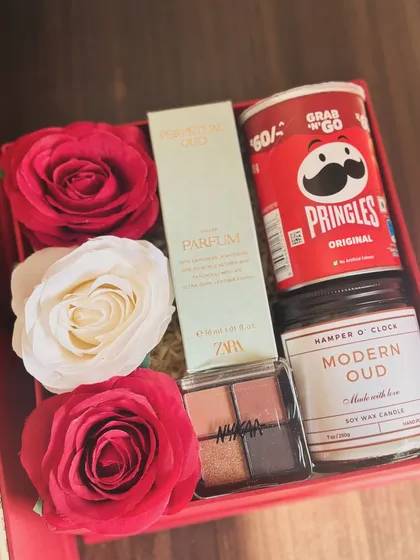 A Valentine's Day hamper for the beauty lover, including a Zara perfume, a Nykaa eyeshadow palette, a "Modern Oud" candle, and Pringles for a fun snack.