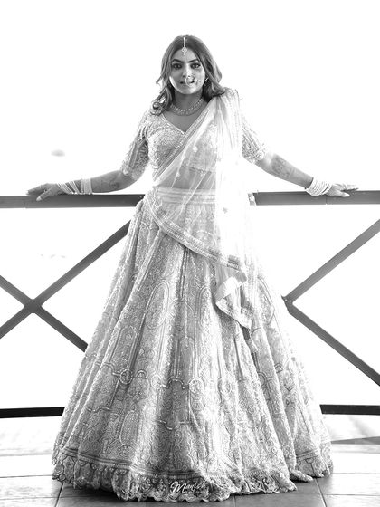 A classic black and white bridal portrait, highlighting the intricate details of her attire and her serene expression.