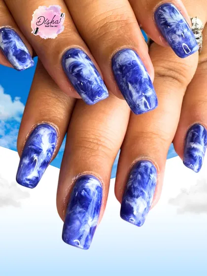 Sky vibes on your nails. This stunning blue and white marble design looks like clouds swirling in the sky.