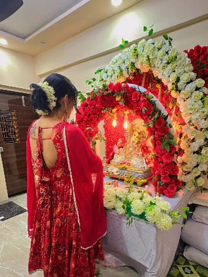A client admiring the beautiful Ganpati mandap I created. The arch of red and white roses with a lit backdrop makes for a perfect spot for prayers and photos.