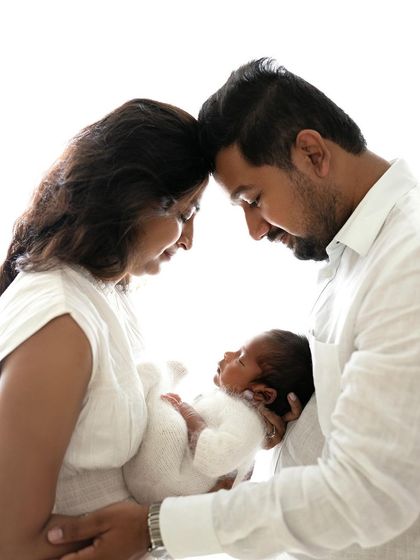 An intimate portrait of new parents with their baby. The forehead-to-forehead pose is a classic way to show connection and love.