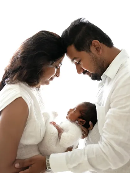 A classic family pose, with mom and dad touching foreheads as they hold their new baby. This is a portrait of pure love and unity.