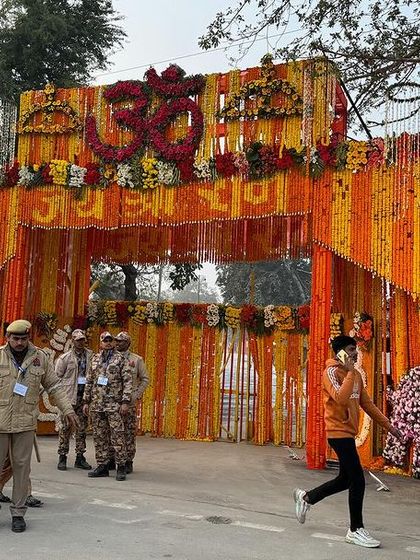 An entrance gate in Ayodhya, heavily decorated with marigold flowers and the 'Om' symbol. The sheer scale of the decorations and the movement of people created a lively scene.