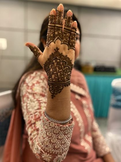 A client showing off her beautiful, intricate back-hand design. The pattern is dense and traditional, perfect for a wedding guest or festive party.