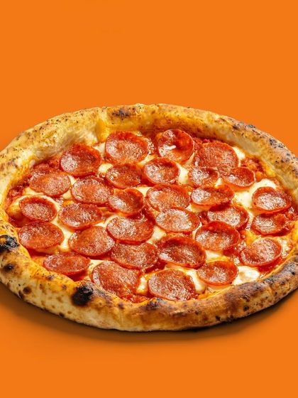 A classic pepperoni pizza against a vibrant orange background, creating a bold and eye-catching image for e-commerce.