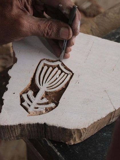 A close-up of a master carver's hands bringing a floral design to life on a teak block. This particular block was created for a collaborative workshop with the Fabric Workshop Museum in Philadelphia.