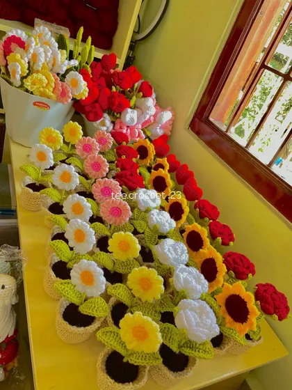 A colorful lineup of my potted daisies, sunflowers, and roses on my workbench, showcasing the variety of handmade flowers available.