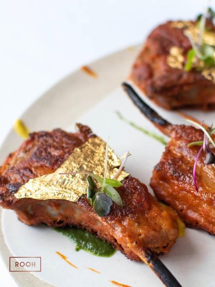 A closer look at a single Golden Vark Lamb Chop. You can see the perfect char on the meat and the delicate placement of the edible gold leaf, a signature of our fine dining experience.