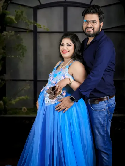 The couple celebrates their baby boy with this happy portrait. They hold up a pair of tiny shoes, a classic and heartwarming prop for any maternity shoot.