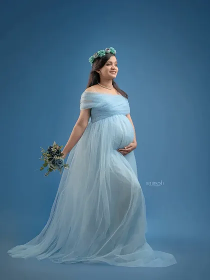 A standing portrait in the same beautiful blue gown, accessorized with a matching floral crown and bouquet. This shows how we can create multiple looks from a single gown choice.