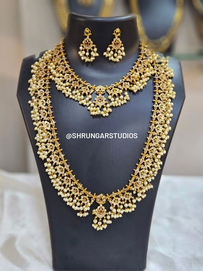 A beautiful bridal combo set with a necklace and matching long haar, both featuring intricate floral motifs and pearl drops.