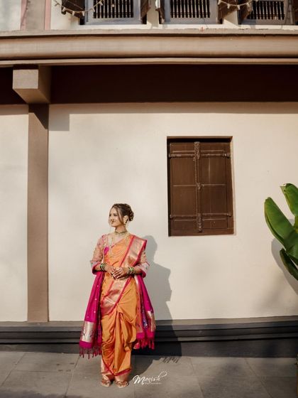 A full-length portrait of the bride in her beautiful orange and pink saree, capturing the grace and beauty of Marathi bridal fashion.