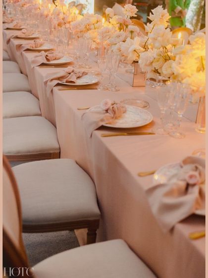 A long view of the blush-toned tablescape, with rows of white chairs and glowing candles creating a romantic and memorable ambiance.