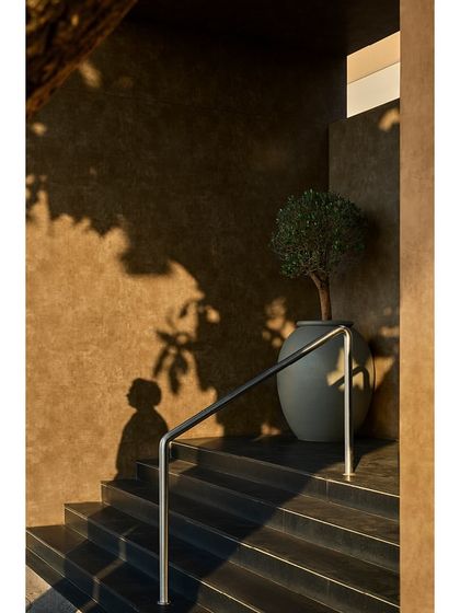 The play of light and shadow on the textured entrance walls at dusk creates a dramatic and artistic effect.