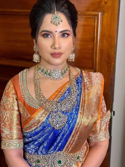 A portrait of the bride, highlighting the intricate details of her custom orange brocade blouse and her stunning diamond and emerald jewelry set.