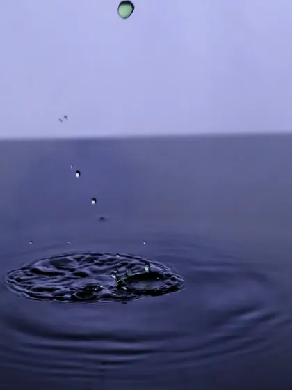 The moment just before the splash, this photo captures a single droplet falling towards the water's surface, building anticipation.