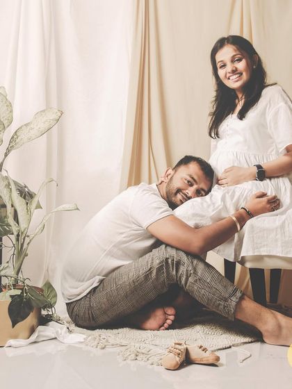 A sweet and candid moment from a maternity session, where the father-to-be rests his head on the baby bump. The warm lighting and natural props create a cozy and heartfelt atmosphere.