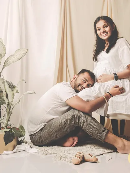 A sweet and classic maternity pose, with the partner listening to the baby bump. We use simple props like tiny baby shoes to add a touch of warmth.