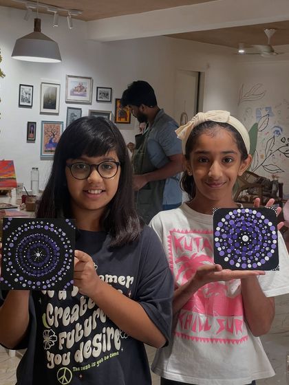 These two artists are showing off the dot mandala paintings they created in a workshop. This meditative art form is great for developing focus and an eye for detail.