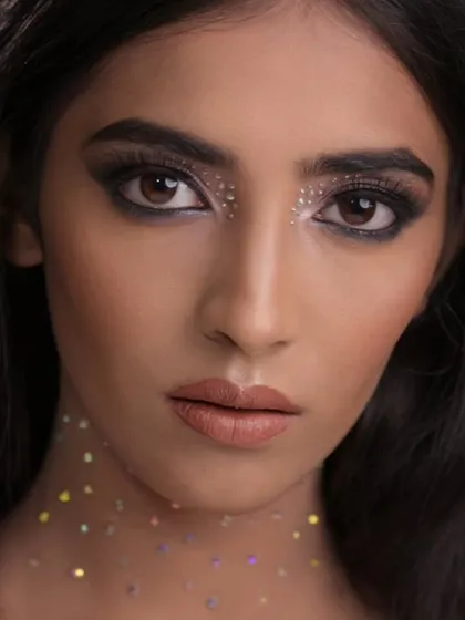 An ethereal look featuring a smokey eye base with scattered glitter under the eyes and on the neck, creating a celestial effect.