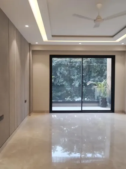 An unfurnished room with finished walls, flooring, and ceiling with integrated lighting. The large sliding glass door connects the interior to the outdoors, filling the space with natural light.