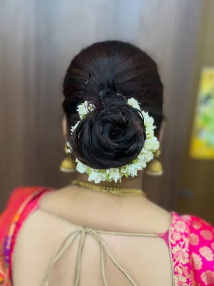 A back view of the classic bun hairstyle, completely encircled by fragrant mogra flowers. This is a timeless choice for silk sarees.