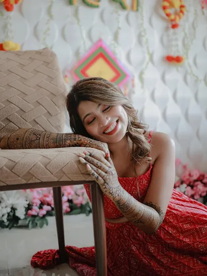 A sweet and candid moment. The bride rests her head on her arms, smiling with her eyes closed, lost in the happy thoughts of her upcoming wedding.