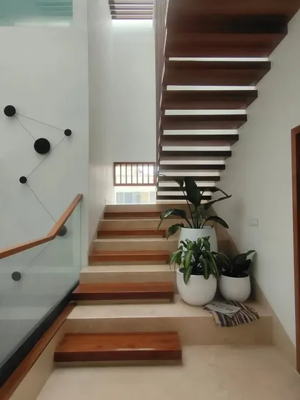 A staircase is more than just for moving between floors; it's a design feature. In this home, I used clean lines, a glass railing, and warm wood treads, placing planters at the landing to make the journey through the house a pleasant experience.