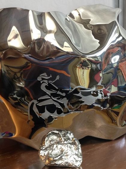 "Bull Series II" is a tabletop sculpture where the engraving of a bull rider is distorted and animated by the curved, reflective surface.