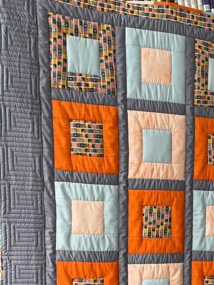A detail shot of the block quilt, showing the ruler work on the border and the simple quilting on the blocks.
