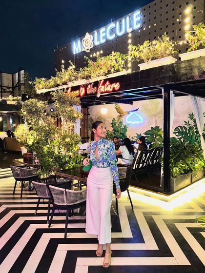 The complete look in front of the restaurant's neon sign. This outfit is a perfect example of smart casual dressing for a chic night out.
