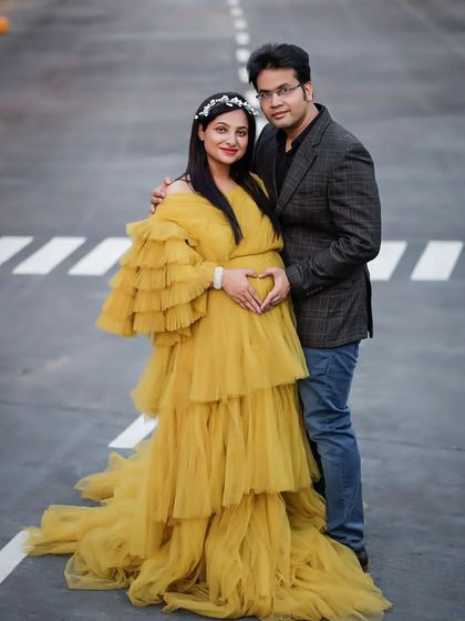 A happy couple posing in our mustard yellow tiered tulle gown. This dress is perfect for outdoor shoots and adds a bright, joyful pop of color to your maternity photos.