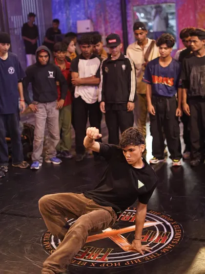 A b-boy hits a clean freeze on the branded floor mat at our Hiphop Elements jam. The energy from the surrounding crowd is a key part of the battle atmosphere we cultivate.