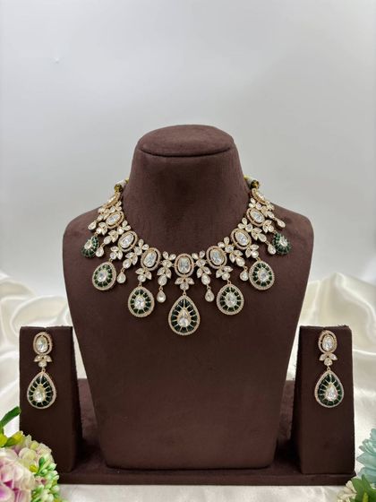 A beautiful Moissanite and AD necklace set with green or red Meenakari detailing. The combination of oval and teardrop stones gives this piece a unique and luxurious appeal.