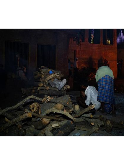 A family prepares a funeral pyre, a solemn and intimate ritual performed in the open.