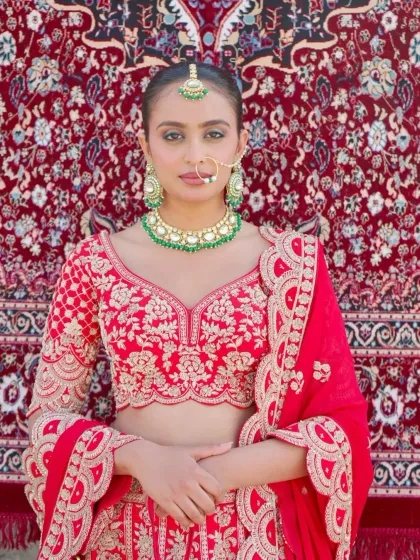 A close-up of the bride's look, showing the detailed embroidery on the blouse and the beautiful bridal jewelry. This red lehenga is all about timeless elegance.