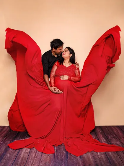 Creating art with fabric. In this studio shot, we use a dramatic red gown with extended fabric wings to create a stunning, symmetrical portrait that frames the couple's loving gaze.