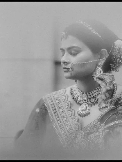 A soft and dreamy black and white bridal portrait, focusing on her intricate jewelry and serene expression.