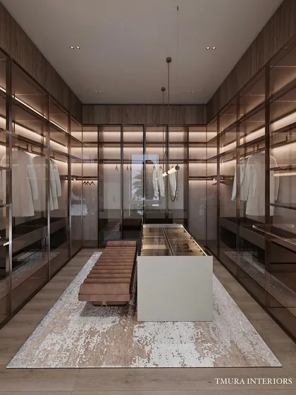 This is our vision of a modern walk-in wardrobe. We used smoked glass doors, integrated LED lighting, and warm wood veneers to create a boutique-like experience. The central island features a custom leather-upholstered bench and organized accessory storage.