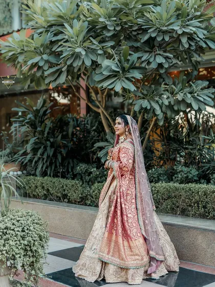 A full-length portrait of the bride in a garden, her beautiful and unique wedding outfit on full display.