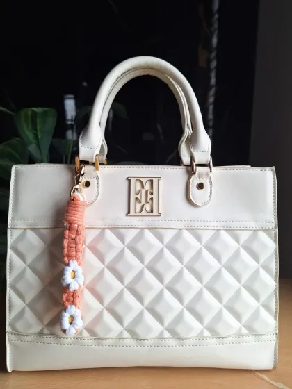 A closer look at our daisy bag charm in a warm peach tone. Each flower is carefully knotted to create a cheerful and durable accessory.