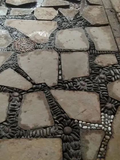 A creative and durable pathway made from irregular flagstones, with decorative pebbles filling the gaps in floral patterns.