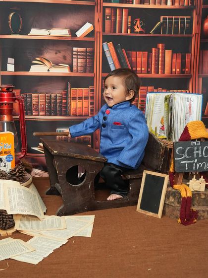 A full view of the 'School Time' setup, complete with a library backdrop, vintage desk, and scattered book pages. This little boy's happy expression shows he's having a great time.