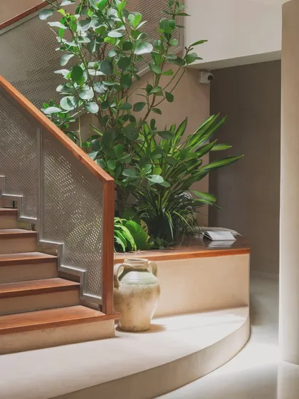 The base of the staircase features a built-in planter and a curved bench, turning a simple transitional space into a beautiful architectural feature.